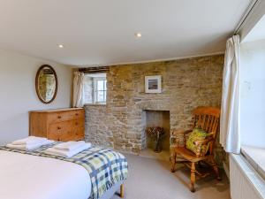 een slaapkamer met een stenen open haard en een bed en een stoel bij 3 Bed in Isle of Purbeck IC081 in Langton Matravers