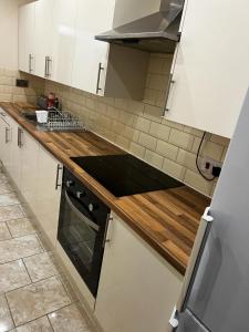 uma cozinha com armários brancos e bancadas de madeira em Nice house near cricket ground em Nottingham