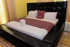 a large bed with a black leather headboard at MONTANA STAY in Ruhengeri