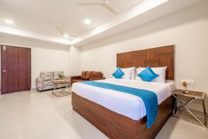a bedroom with a large bed and a chair at Monday Hotels Swarna's The Capital in Vijayawāda
