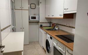 cocina con armarios blancos y lavadora en Room in Apartment - Apartment for 4-5 people 70 m from the beach, en Miami Platja