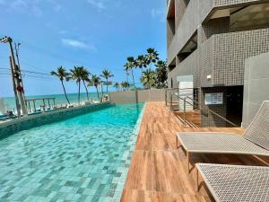 una piscina junto a un edificio con palmeras en Lindo studio com Vista para o Mar, en Maceió