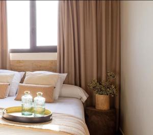 Una cama con dos botellas en una bandeja. en Hotel El Teular en Sueca