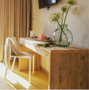 a vase with flowers sitting on a wooden table at Hotel El Teular in Sueca