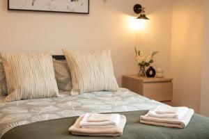 a bed with two towels sitting on top of it at Green Nest Room with private bathroom in Eastbourne