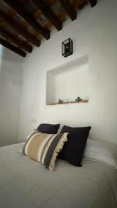 1 cama con almohadas blancas y negras y espejo en Apartamentos Jerez Siglo XIX, en Jerez de la Frontera