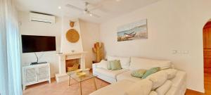 sala de estar con sofá blanco y TV en Villa El Encanto, en Moraira