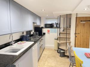 a kitchen with white cabinets and a counter top at Sixpence Cottage, a few steps from the harbour! in St Ives