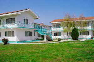 a large white building with blue stairs in a yard at Vilele Delfin in Costinesti