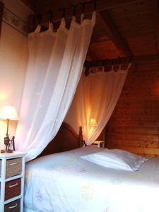 a bedroom with a bed with white curtains at B&B Chalet l'Epinette in Gérardmer