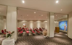 a conference room with red chairs and a large screen at Hotel Cristal in San Carlos de Bariloche