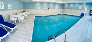 - une grande piscine avec une table et des chaises dans l'établissement Holiday Inn Express & Suites Muskegon - Grand Haven, an IHG Hotel, à Muskegon