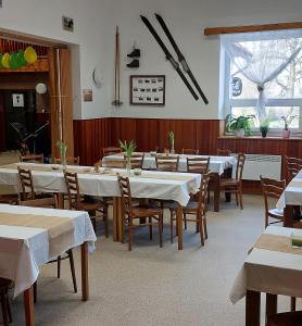 uma sala de jantar com mesas e cadeiras brancas e uma janela em U Dvou rysů em Zdíkov