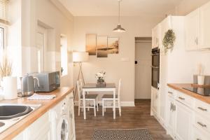 a kitchen with white cabinets and a table with a computer at Spacious 4 bed Edwardian home in Chester - Sleeps up to 7 in Chester