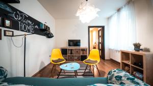 a living room with yellow chairs and a table at Heart of the city II in Braşov