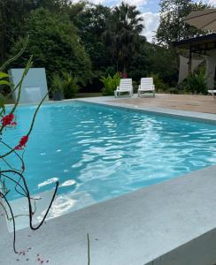 a swimming pool with two white chairs next to it at Casa Buena Karma in Ojochal