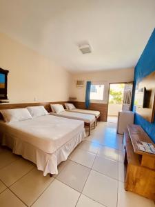 a hotel room with two beds and a table at Hotel Porto das Ancoras in Porto Seguro