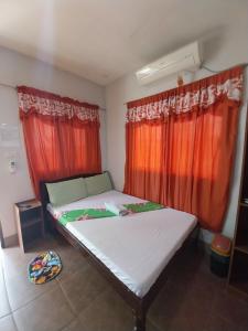 um pequeno quarto com uma cama com cortinas vermelhas em TAVERN ROOMS FOR RENT em Panglao City