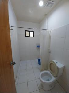 a white bathroom with a toilet and a window at TAVERN ROOMS FOR RENT in Panglao