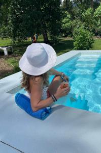 Una niña con sombrero sentada en una piscina en Casa Buena Karma, en Ojochal