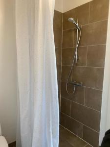 a shower with a white shower curtain in a bathroom at Countryside home 300m to the Fishing river Lille Ø in Langå