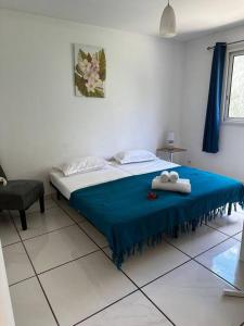 een slaapkamer met een bed met een blauwe deken en een stoel bij Villa Karo Coco in Saint-Leu