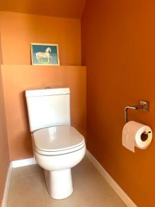 ein Badezimmer mit einem weißen WC in einer orangefarbenen Wand in der Unterkunft Duplex zona calvario in Tandil + 4 Fotos