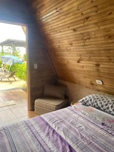 1 Schlafzimmer mit einem Bett und einem Stuhl sowie einer Terrasse in der Unterkunft Chácara Recanto das Aves in Pilar do Sul
