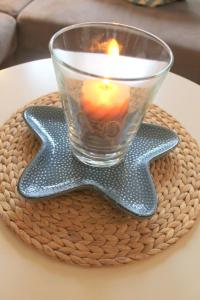 una candela in un bicchiere su una stella di vimini sul tavolo di Ferienwohnung Strandfee, App 01 in ruhiger strandnaher Lage a Grömitz