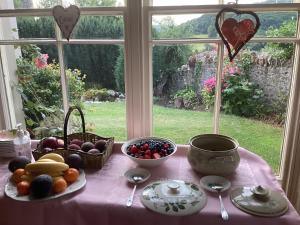 a table with fruits and vegetables on a table in front of a window at Bryn Guest House in Conwy