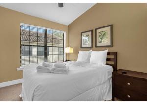 1 dormitorio con 1 cama blanca grande y toallas. en Deluxe Townhome - 5 minutes from Disney, en Orlando