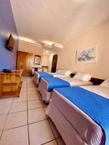 a hotel room with four beds in a row at Hotel Porto das Ancoras in Porto Seguro