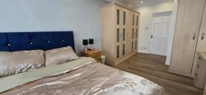 a bedroom with a large bed with a blue headboard at Wood, Double Room in London in Great Warley Street