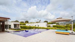 una piscina con sombrilla junto a una casa en Hermosa casa campestre a 9 minutos de la ciudad, en Pereira
