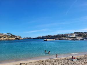 a group of people playing in the water on a beach at El patio de Iria in Porto Cristo