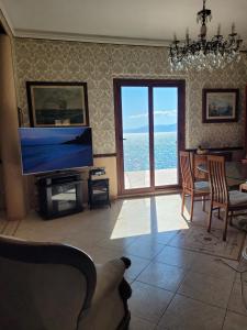 a living room with a television and a view of the ocean at Villa Rosa in SantʼElia