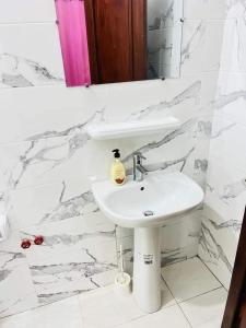a white bathroom with a sink and a mirror at Timba-Day229 in Abomey-Calavi