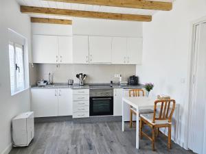 a kitchen with white cabinets and a table and chairs at Casa de Lupa - Camariñas - Costa da Morte in A Coruña +16 photos