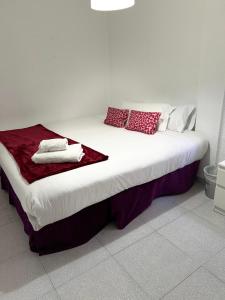 Una cama blanca con almohadas rojas y blancas. en Habitación por días, en Catarroja