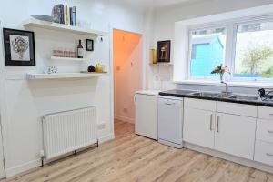 a kitchen with white cabinets and a sink and a window at Erradale in Campbeltown