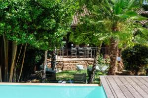 a swimming pool with palm trees and a table and chairs at L'ACADEMIE in Leynes