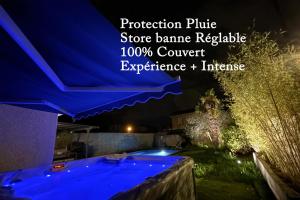 Unique! jacuzzi privé 35°C + cinéma Villa entière في ميزيو: مسبح في الليل مع مظلة زرقاء