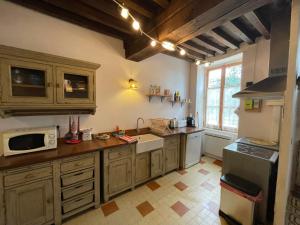 a large kitchen with wooden cabinets and a microwave at Gîte La Bancale in Lormes