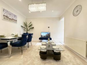 a living room with a dining room table and a clock at Enchanting 3Bed, 2 Reception Apartment w/ Private Garden & Parking in Ilford in Barking