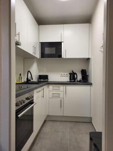 a kitchen with white cabinets and a black appliance at Austernfischer - b63685 in Wendtorf