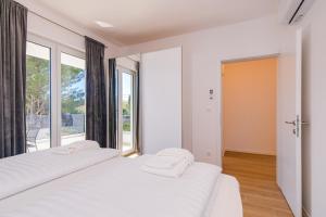 - une chambre avec 2 lits blancs et une grande fenêtre dans l'établissement Apartment Mialis, à Krk