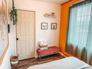 a bedroom with orange walls and a door and a red bench at Auberge Mandala in Saint Mathieu Du Parc