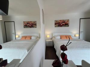2 Betten in einem weißen Zimmer mit 2 Spiegeln in der Unterkunft Guesthouse Villa Stanger 2 in Lovran