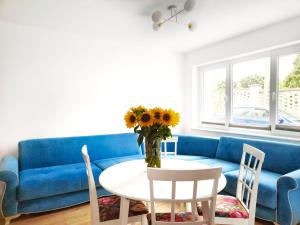 uma sala de estar com um sofá azul e uma mesa com flores em APARTAMENTY Charzykowy em Charzykowy