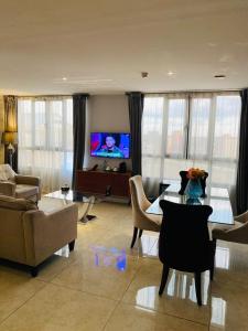 Boun's Hotel في ياوندي: غرفة معيشة مع طاولة وتلفزيون